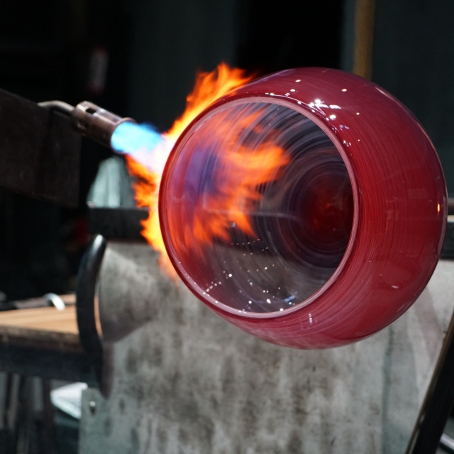 A red molten glass bowl that's engulfed in flames
