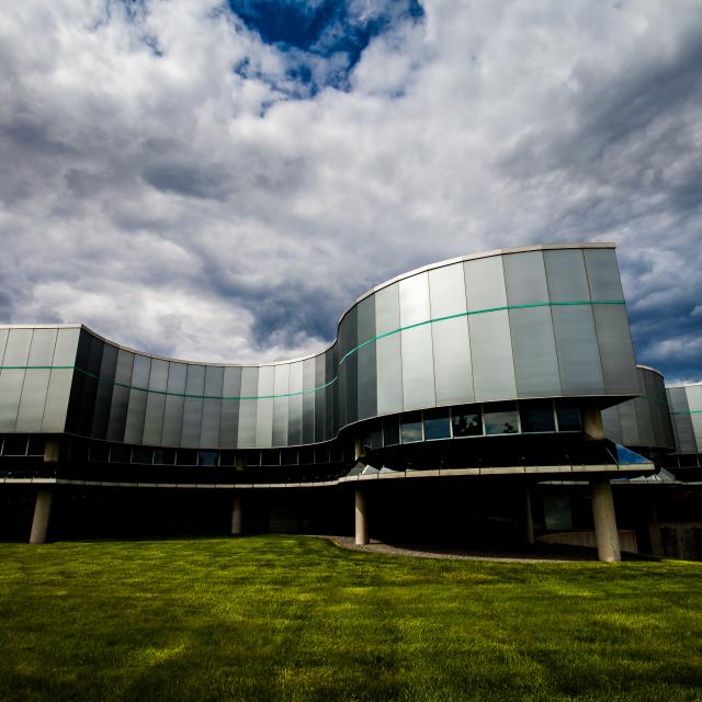 The outside of Birkerts Building is shown from a low angle and the sky above is filled with clouds