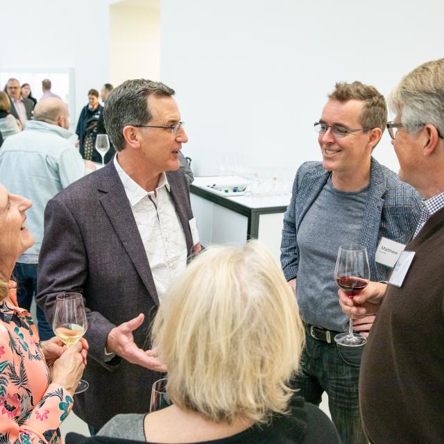 A group of members enjoy conversation and wine at the opening of 2019's New Glass Now exhibition