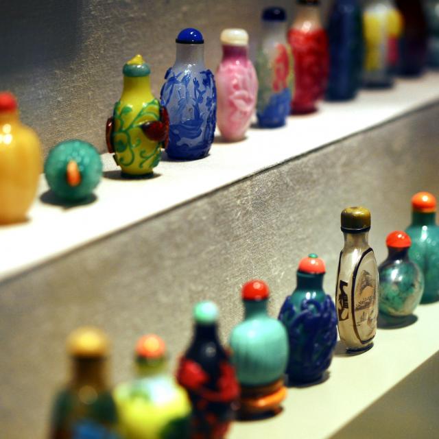 Two rows of multicolored small glass bottles 
